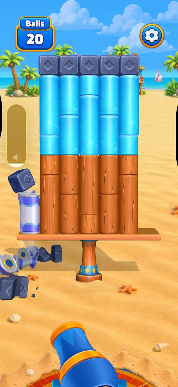 A taller Smash Fest structure: columns of ice blocks and wooden logs topped with stone cubes, with knocked-off pieces already scattered in the sand